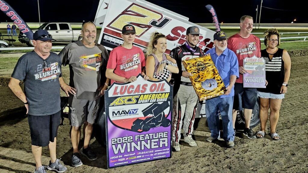 Zach Blurton and his family and crew standing in Victory Lane at WaKeeney after Blurton's first national American Sprint Car Series win